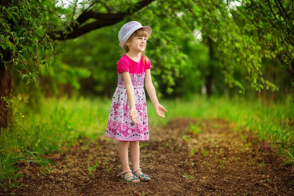 Malé radostné holčičky ve světlých šatech chodit v zahradě — Stock fotografie