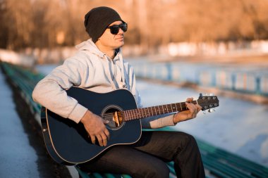 İskambil gitar ve şarkı, müzik konsepti basamaklarında oturan genç adam