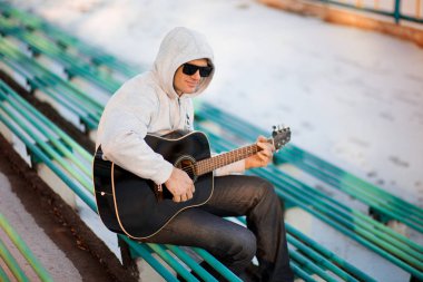 İskambil gitar ve şarkı, müzik konsepti basamaklarında oturan genç adam