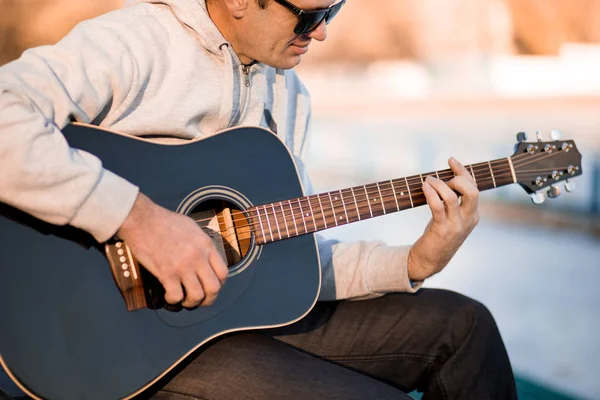 Joven sentado en los escalones tocando la guitarra y cantando, concepto musical — Foto de Stock