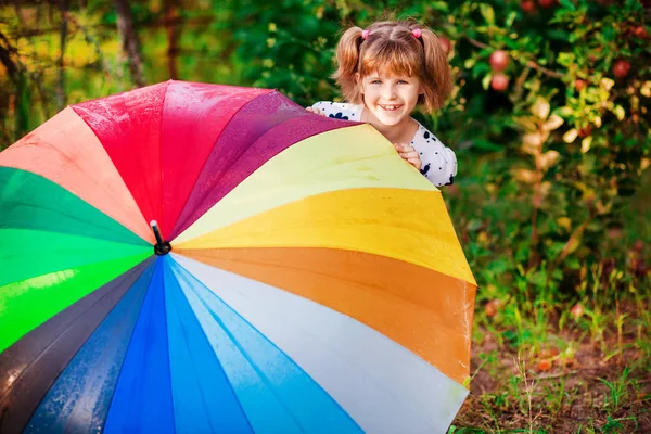 Ragazza felice passeggiata con ombrello multicolore sotto la pioggia — Foto Stock