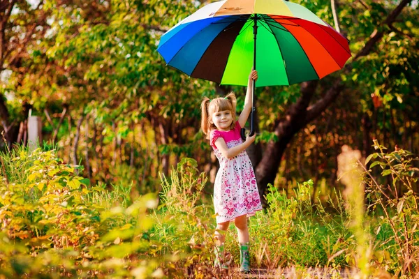 Fröhliches Kindermädchen spaziert mit buntem Regenschirm im Regen — Stockfoto