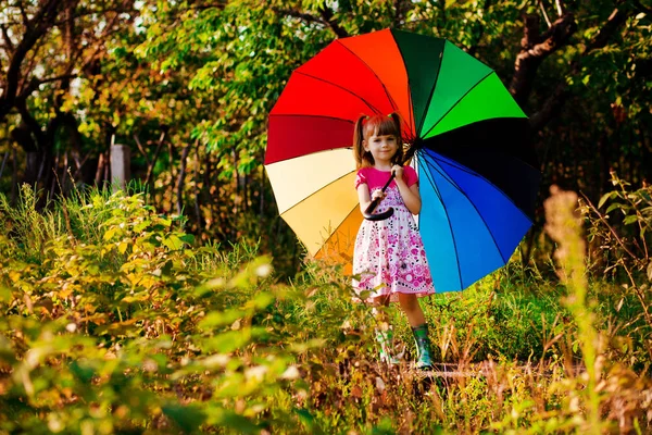 Menina menina feliz andar com guarda-chuva multicolorido sob chuva — Fotografia de Stock