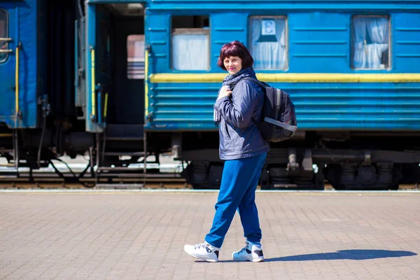 鉄道駅でのバックパックと 60 歳の女性。旅行の概念 — ストック写真