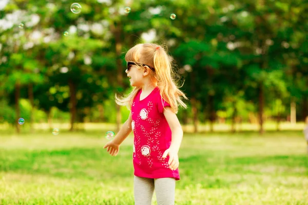 Boldog szőke kislány fúj szappanbuborékok nyári park — Stock Fotó