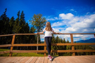 Teras çit üzerinde uzun saçlı genç kadın zevk güzel bir dağ manzarası