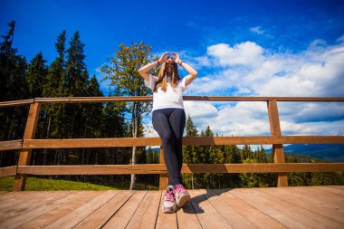 Teras çit üzerinde uzun saçlı genç kadın zevk güzel bir dağ manzarası