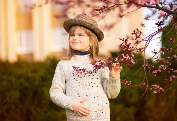 Portrait printanier, adorable petite fille au chapeau promenade en fleurs jardin sur le coucher du soleil — Photo