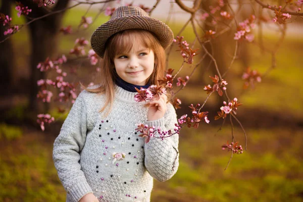 Portrait printanier, adorable petite fille au chapeau promenade en fleurs jardin sur le coucher du soleil — Photo