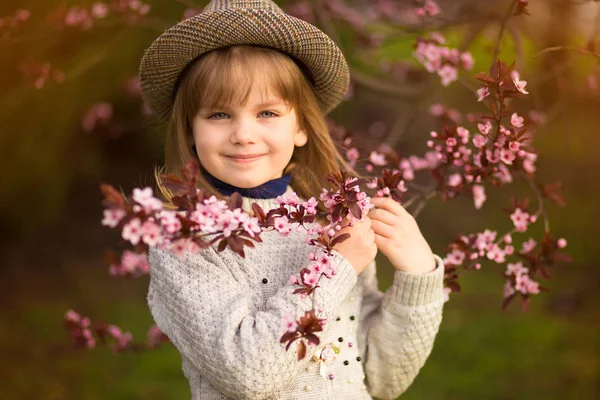 Portrait printanier, adorable petite fille au chapeau promenade en fleurs jardin sur le coucher du soleil — Photo