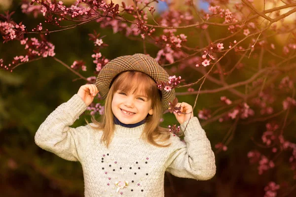 Retrato da mola, menina adorável no passeio do chapéu no jardim da árvore da flor no por do sol — Fotografia de Stock