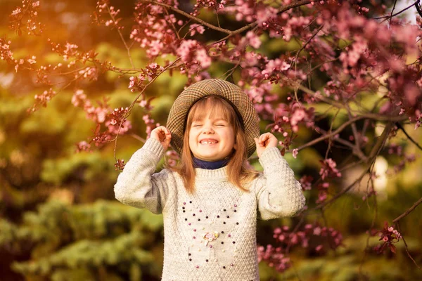 Lente portret, schattig klein meisje in Hat Walk in Blossom tree Garden op zonsondergang — Stockfoto