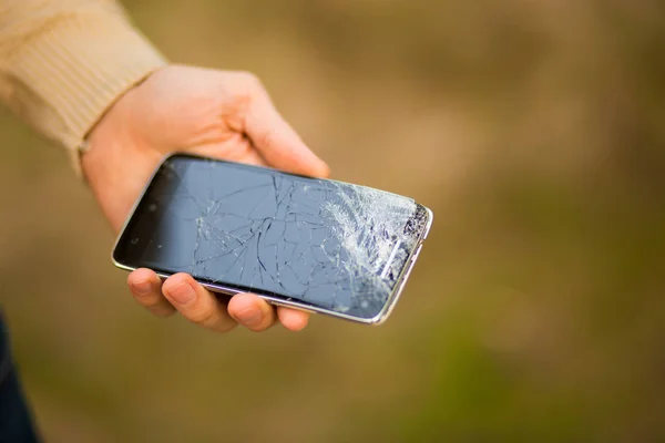 Joven hombre mantenga roto la pantalla del teléfono inteligente. Teléfono roto en la mano — Foto de Stock