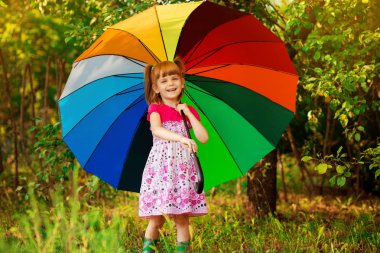 Mutlu çocuk kız yürümek yağmur altında çok renkli şemsiye ile