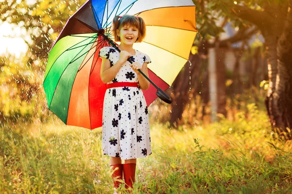 Happy child girl walk with multicolored umbrella under rain — Stock Photo, Image