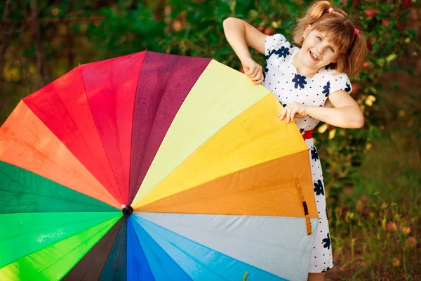 Menina menina feliz andar com guarda-chuva multicolorido sob chuva — Fotografia de Stock