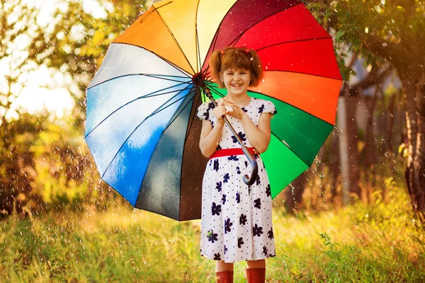 Happy child girl walk with multicolored umbrella under rain — Stock Photo, Image