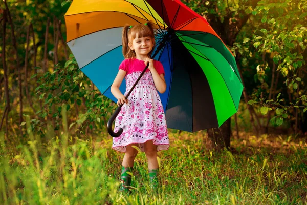 Menina menina feliz andar com guarda-chuva multicolorido sob chuva — Fotografia de Stock