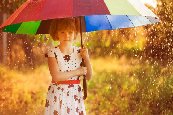 Menina menina feliz andar com guarda-chuva multicolorido sob chuva — Fotografia de Stock