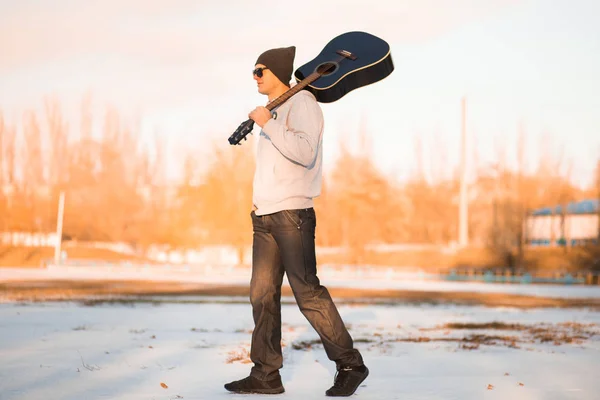 Jeune homme marche dans la rue avec guitare et chant — Photo