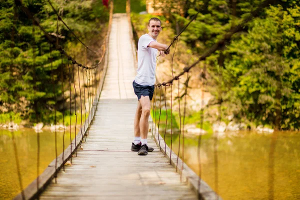 Jeune homme heureux sur le pont sur la rivière en automne nature avec moun — Photo