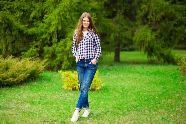 Jeune fille marche le long en veste blanche et jeans par parc — Photo