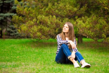 Çekici genç bir kadın, arka planda günbatımıyla parkta eğleniyor..