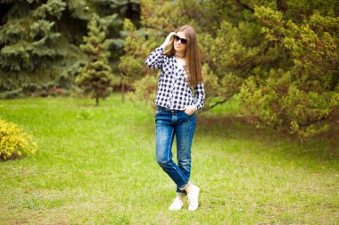 Yaz günlerinde rahatlama. Genç kız güneş gözlüğü parkta yürümek