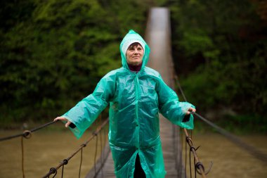 Yaşlı kadın 60 yaşında Orman Yürüyüş menteşeli köprü tarafından Crossing River