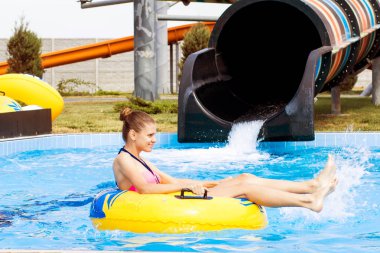 mutlu kadın kauçuk halka turuncu slayt aqua park tarafından aşağı gidiyor. Yaz tatili. Hafta sonu resort