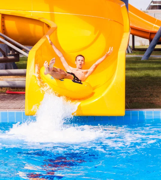 Grappig opgewonden man genieten van zomer vakantie in waterpark paardrijden gele float lachen. — Stockfoto