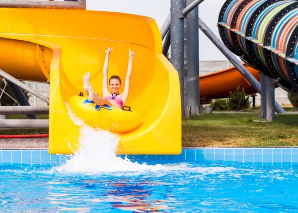 Happy woman going down on the rubber ring by the orange slide in the aqua park. Summer Vacation. Weekend on resort — Stock Photo, Image