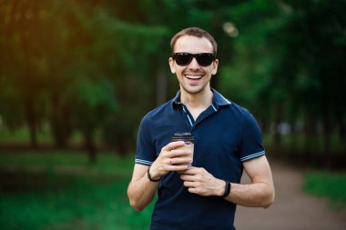 Taze kahvenin tadını çıkarıyorum. Tek kullanımlık bardakla gezen yakışıklı genç adam ve caddede yürürken gülümsüyor.