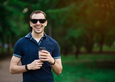 Taze kahvenin tadını çıkarıyorum. Tek kullanımlık bardakla gezen yakışıklı genç adam ve caddede yürürken gülümsüyor.