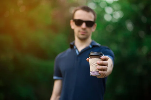 Disfrutando del café fresco. Hombre joven guapo en ropa casual sosteniendo taza desechable y sonriendo mientras camina por la calle de la ciudad —  Fotos de Stock