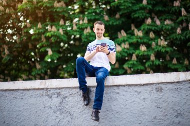 Yakışıklı adam sokakta yürümek ve açık havada bir cep telefonu yla mesajlaşma. Yaşam tarzı kavramı