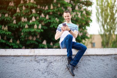 Yakışıklı adam sokakta yürümek ve açık havada bir cep telefonu yla mesajlaşma. Yaşam tarzı kavramı