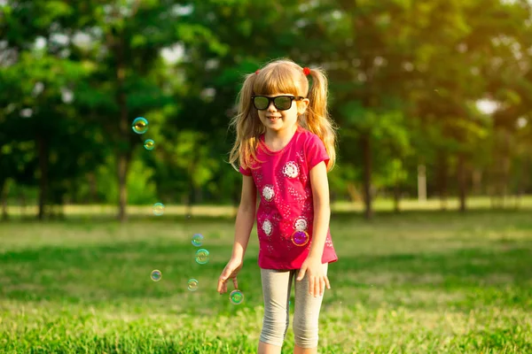 Niedliches weibliches Kind fängt Seifenblasen in der sommerlichen Natur — Stockfoto