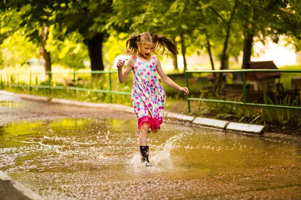 Kisgyerek lány végigfut egy pocsolya. nyári szabadtéri — Stock Fotó