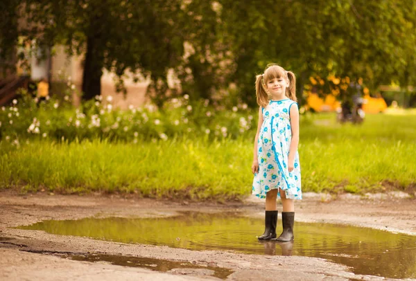 Ein kleines Mädchen rennt durch eine Pfütze. Sommer im Freien — Stockfoto