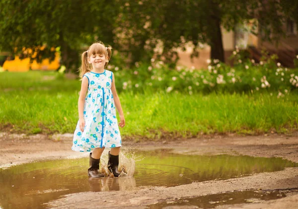 Ein kleines Mädchen rennt durch eine Pfütze. Sommer im Freien — Stockfoto