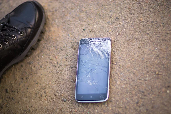 Persona que recoge el teléfono inteligente roto con la pantalla agrietada en tierra — Foto de Stock