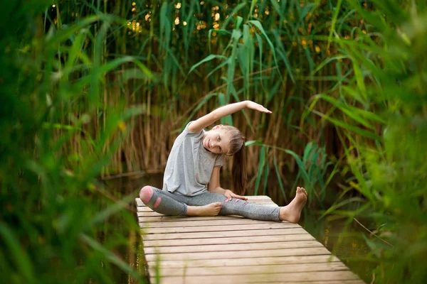 Criança fazendo exercício na plataforma ao ar livre. Estilo de vida saudável. Yoga menina — Fotografia de Stock