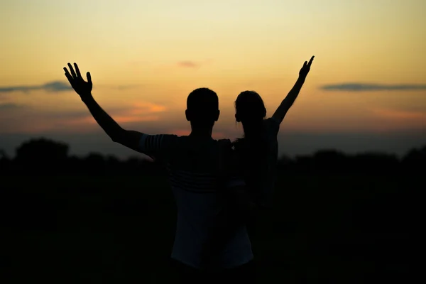 Silhouettes of father and daughter on his shoulders with hands up having fun, against sunset sky. Parenthood, family activities, beach holiday and vacation, support and love themes — Stock Photo, Image