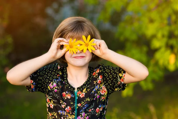 Criança com olhos de flores no parque de verão verde — Fotografia de Stock