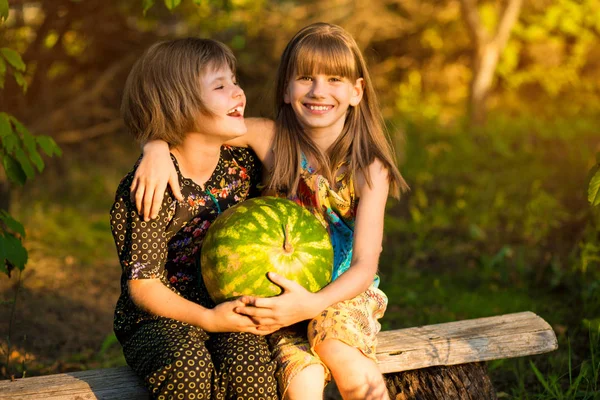 Due sorelline divertenti che mangiano anguria all'aperto in una calda e soleggiata giornata estiva. Cibo sano per bambini piccoli . — Foto Stock