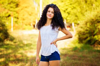 Çok kıvırcık kadınla çimenlerin üzerinde güneşli bir günde poz