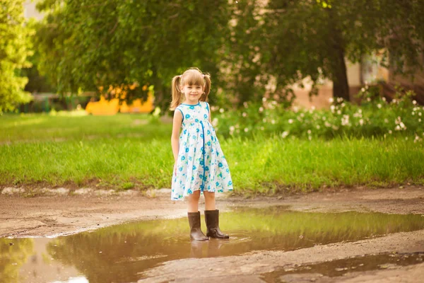 Маленька дівчинка біжить крізь калюжу. літо на відкритому повітрі — стокове фото