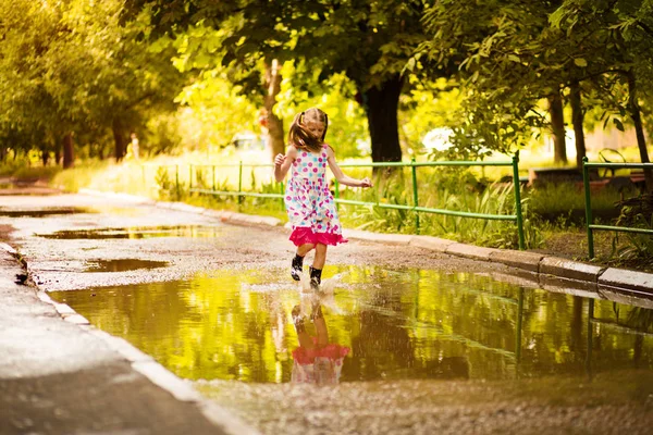 Little kid girl runs through a puddle. summer outdoor — Stock Photo, Image