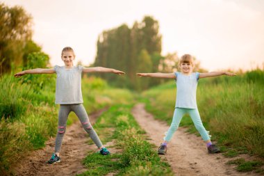 İki küçük kız kardeş dışarıda egzersiz yapıyor. Sağlıklı yaşam tarzı. Yoga